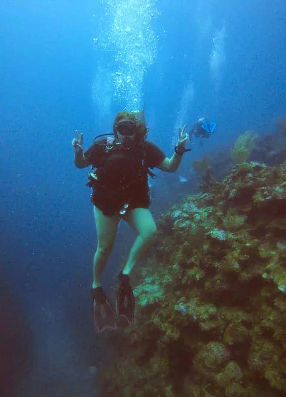 tasha amy diving posing with peace signs underwater near Ambergris Caye's Barrier Reef, one of the best things to do for adventure enthusiasts visiting the island.