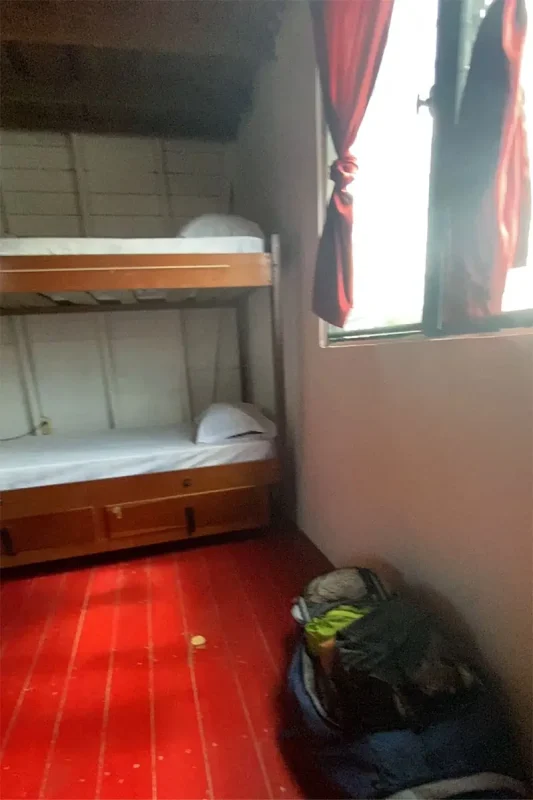 Interior of a hostel room in San Ignacio, featuring wooden bunk beds and a simple, cozy setup. The room is well-lit with natural light coming through the window, creating a welcoming atmosphere for travelers.