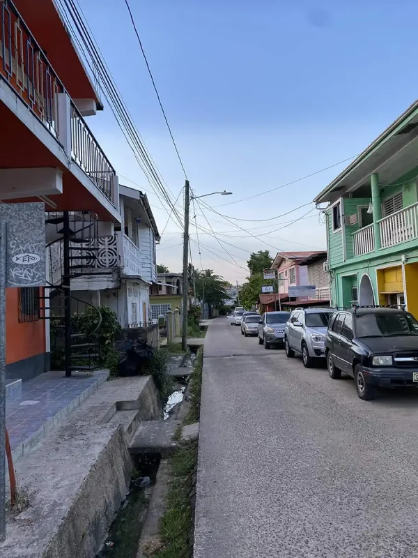 Another street view in San Ignacio, with pastel-colored buildings and a row of parked cars. The street appears calm and residential, highlighting the town's charm and everyday ambiance