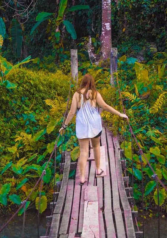 climbing over a wooden bridge that leads to a cave at the blue lagoon in vang vieng