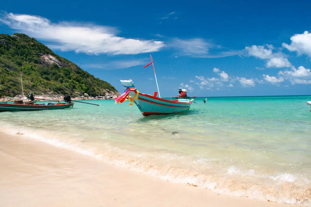 longtail boats lined up transporting tourists to the incredible bottle beach, one of the most beautiful beaches in koh phangan