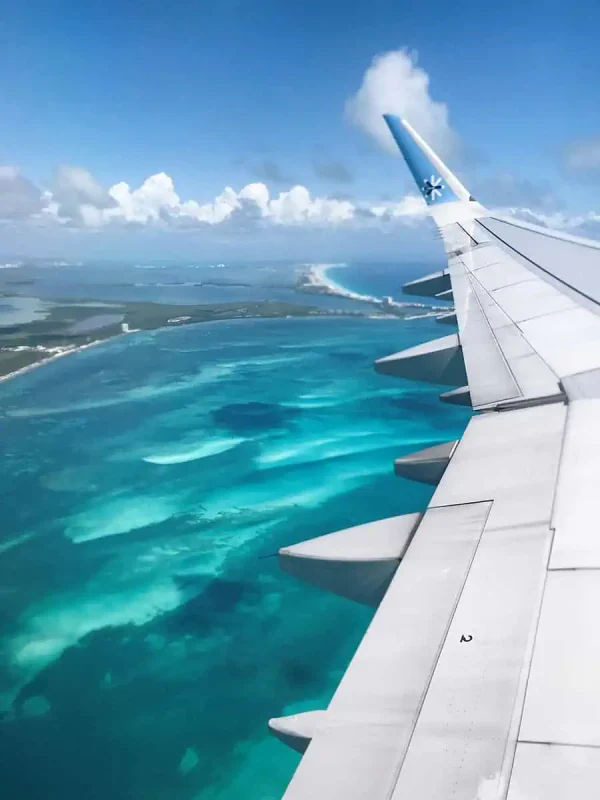 Aerial view from a plane window showcasing the turquoise waters and sandy coastline when flying out of cancun