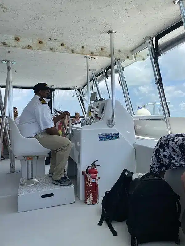 A group of people sitting on a boat traveling from Caye Caulker to Belize City with a captain.
	