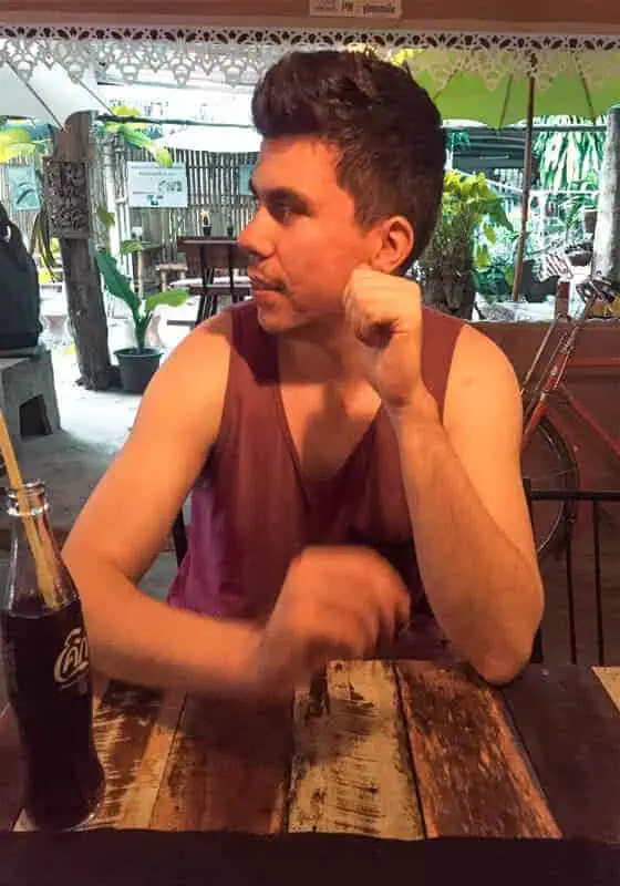 a man at a small restaurant in thailand with a coke on the table