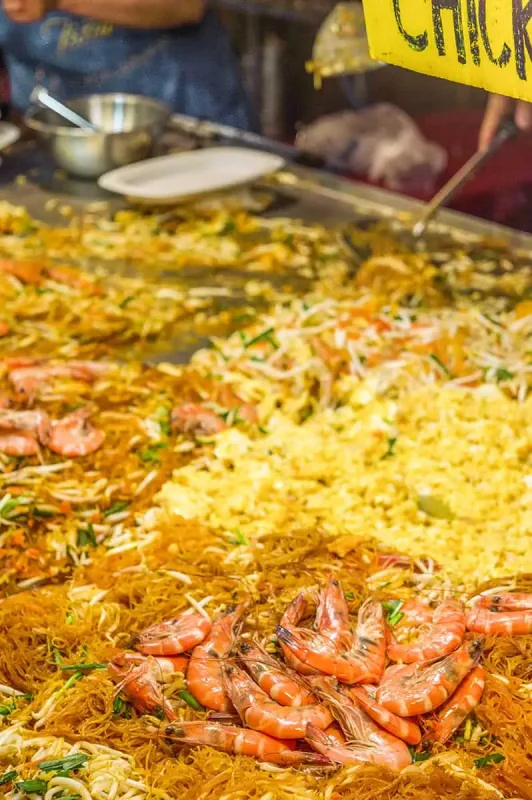 Local vendor serving an array of traditional Thai dishes at a bustling food stall