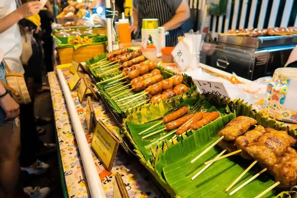 A variety of grilled sausages on banana leaves, showcased at a food stall in the Chiang Mai Sunday market