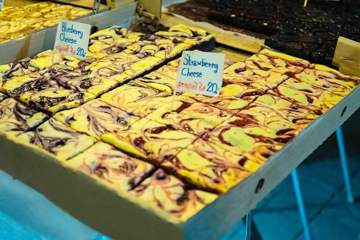 Trays of blueberry and strawberry cheesecake bars attractively arranged for sale at the Sunday market in Chiang Mai.