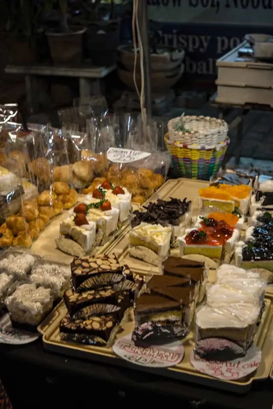 An array of cakes and desserts displayed at a stall, enticing shoppers at the Sunday night market.