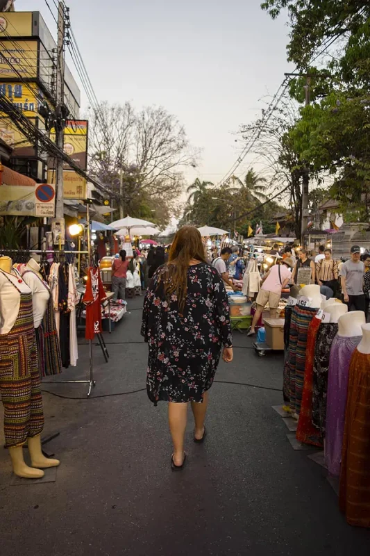 tasha amy browsing through a selection of clothing and accessories at the fashion stalls of the Market in Chiang Mai.