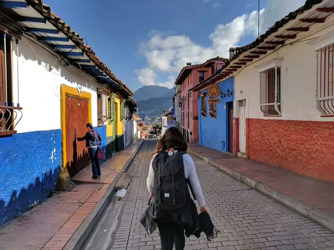 A woman backpacking down a narrow street in Colombia, one of the cheapest countries to travel.