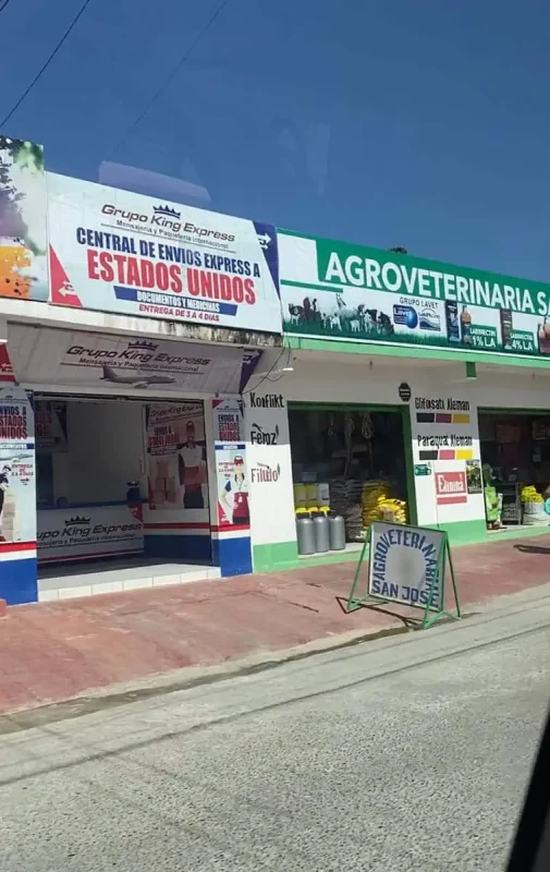 A storefront in Flores with signs for "Grupo King Express" and "Agroveterinaria San Jose," indicating shipping services and veterinary supplies. This everyday street scene provides a glimpse into the local businesses of Flores before heading to Belize City.