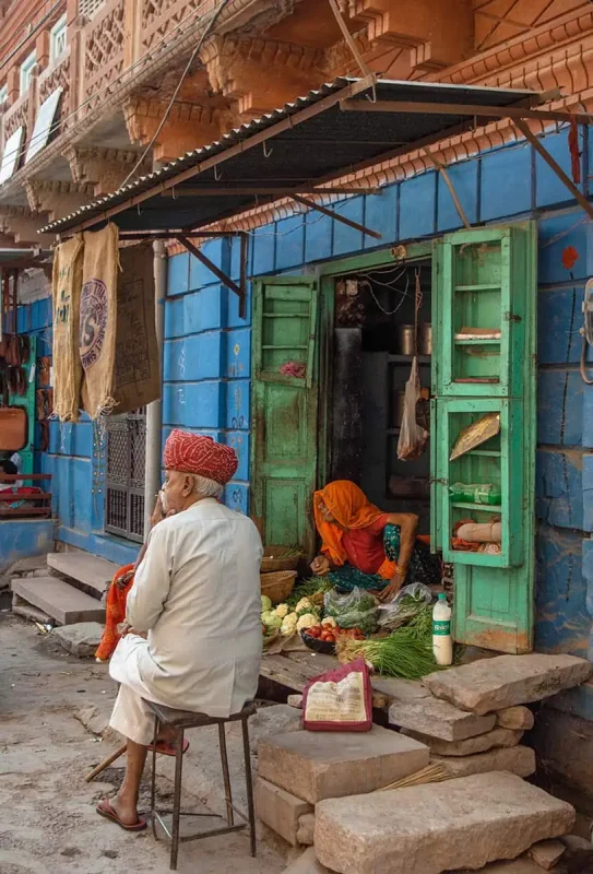 A man sits on a bench in front of a building in jodphur