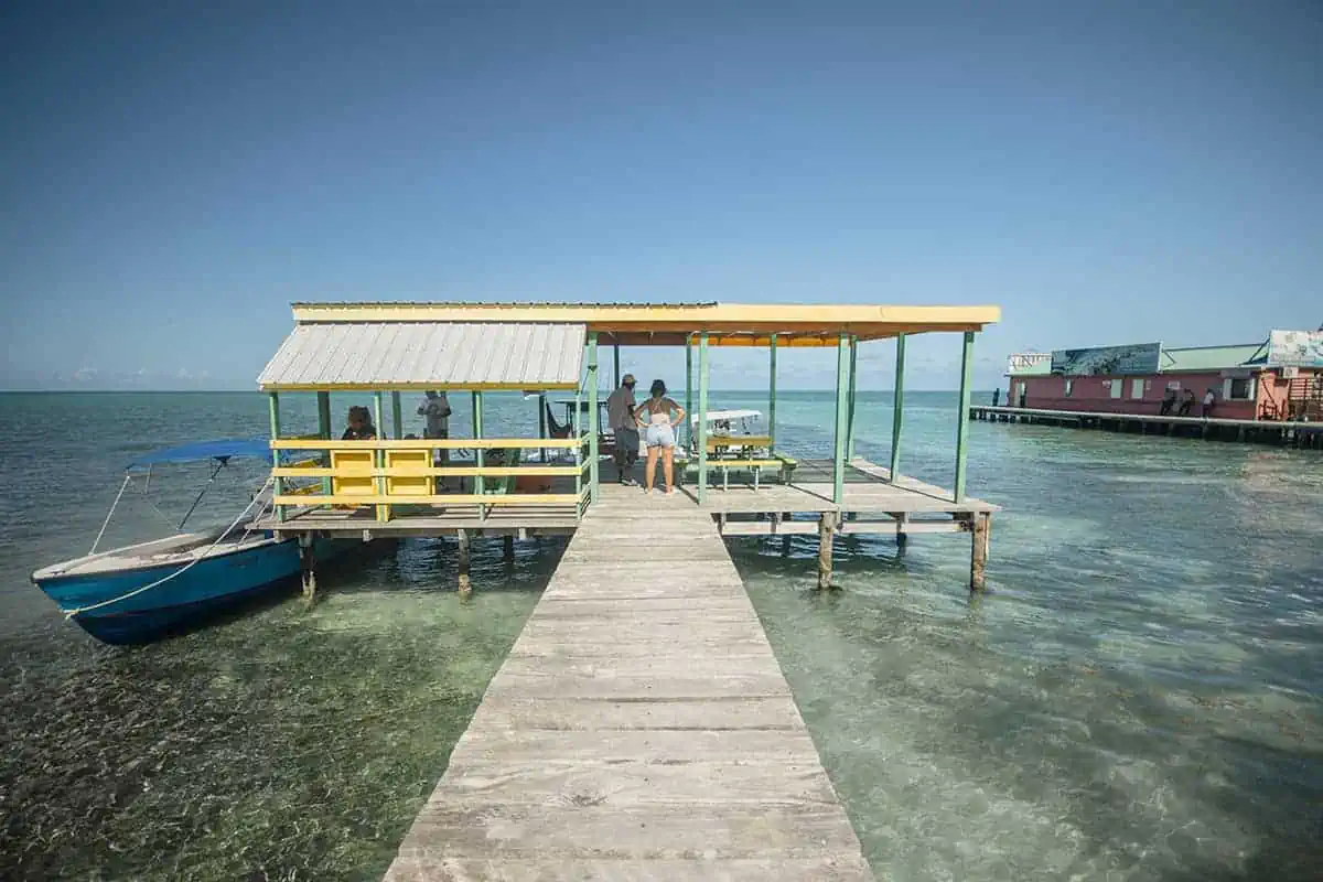 Locals and tourists mingle on a sunny Caye Caulker pier, indicating a safe and sociable environment for leisure activities.