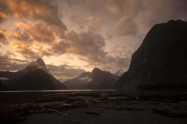 Sunset over Mitre Peak at Milford Sound, New Zealand, with clouds glowing orange and pink, answers the question is milford sound worth it