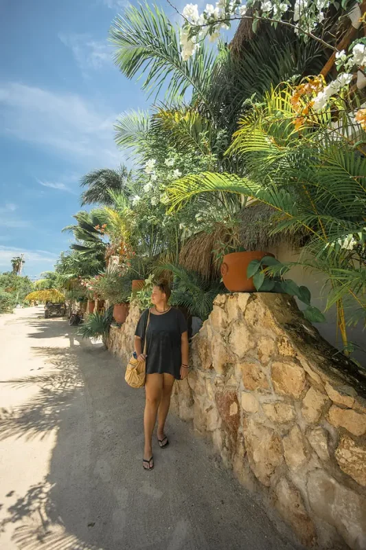 tasha amy walking down a stone path near a palm tree in isla holbox