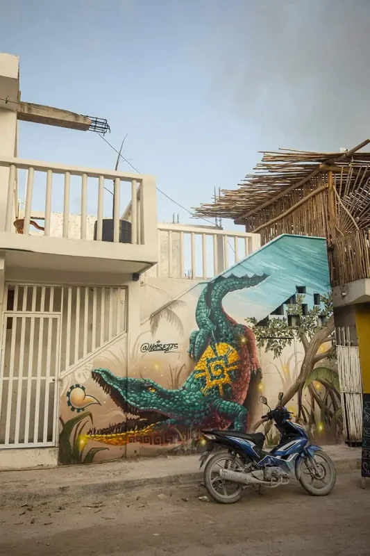 Mexico And Belize Itinerary: From 2 to 5 Weeks 6 A vibrant mural on a building wall depicting a green alligator with intricate designs on its back. A motorbike is parked in front of the mural, illustrating the urban art scene in Mexico.