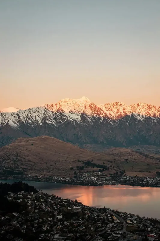 Snowy peaks glow pink under the sunset in Queenstown, New Zealand