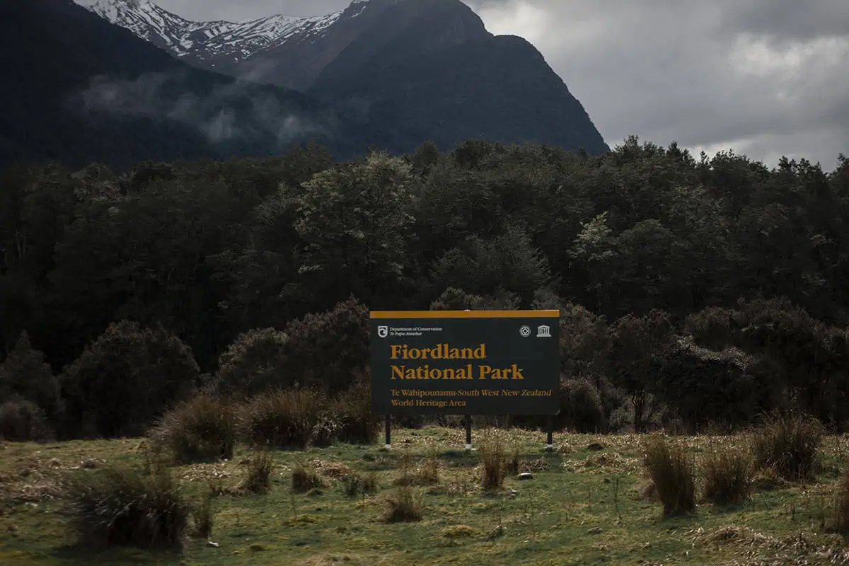 A dark green sign marks the entrance to Fiordland National Park in New Zealand, a Lord of the Rings filming location