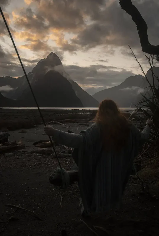 tasha amy gripping the ropes of the handmade Milford Sound swing, looking out over the fjord and dramatic sky.