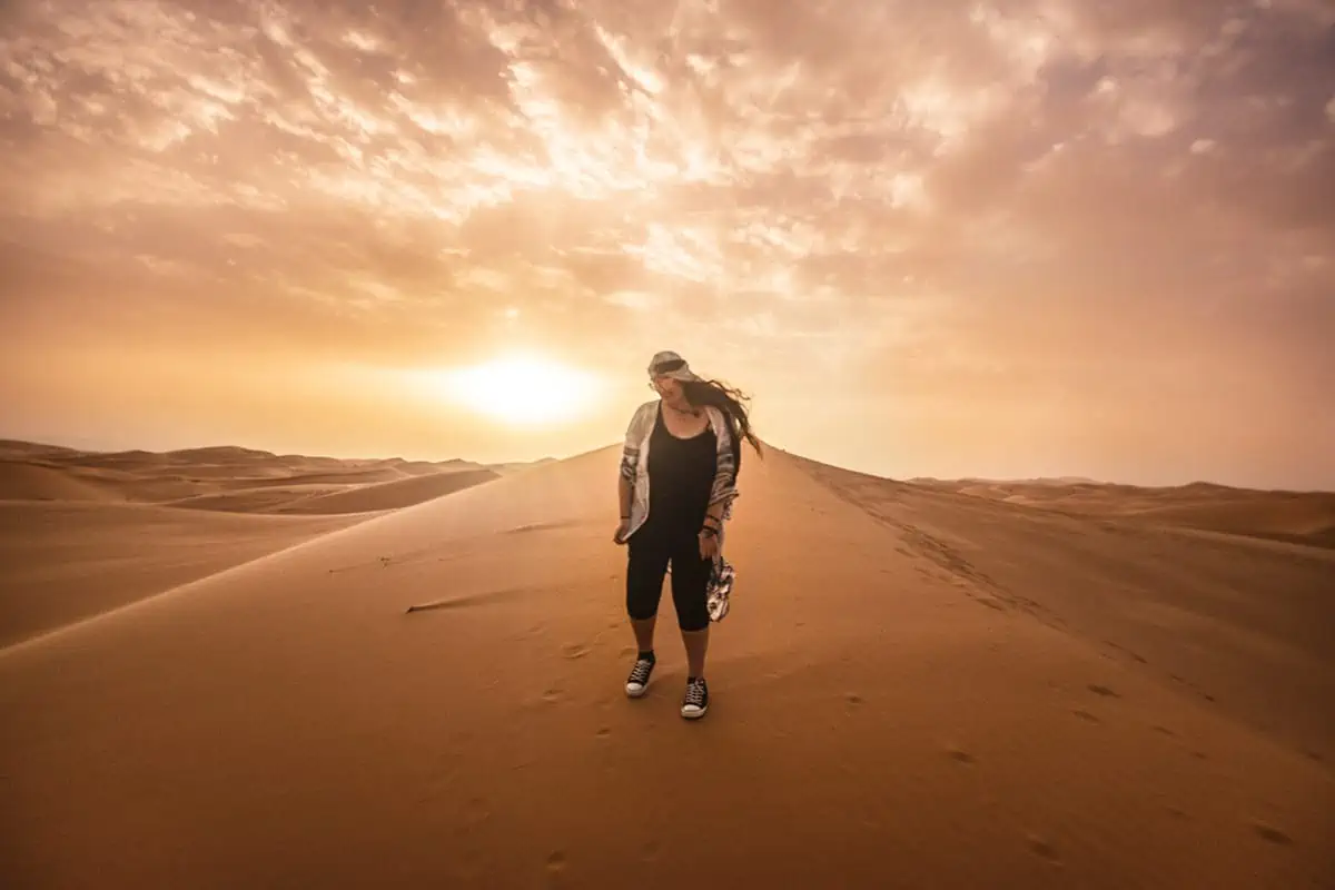 tasha amy standing on a sand dune at sunset in morocco