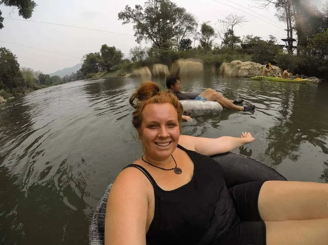 Tasha Amy in a tube on a river with a blurry foreground, giving a relaxed vibe amidst the scenic hills of Vang Vieng tubing.