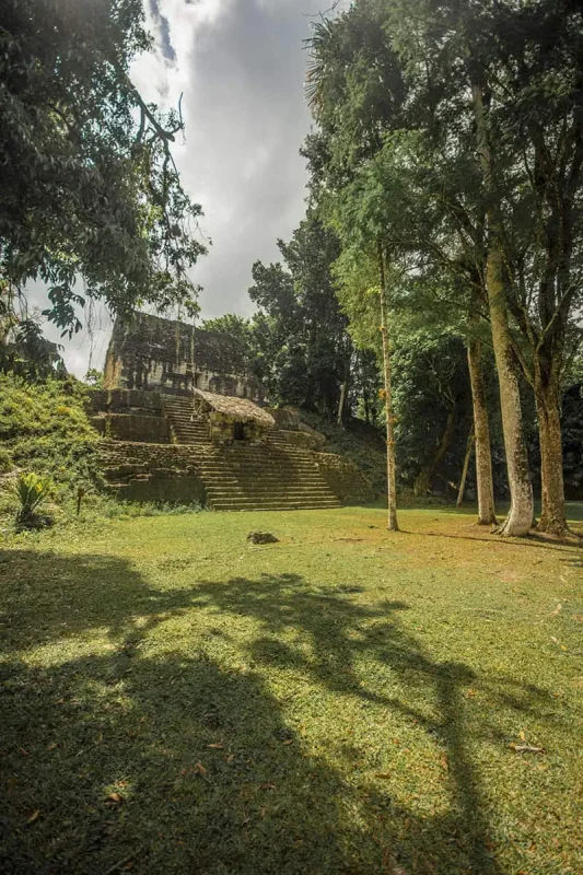 A secluded ancient structure at Tikal enveloped in the jungle ambiance, captured during a serene moment on a tour from San Ignacio.
