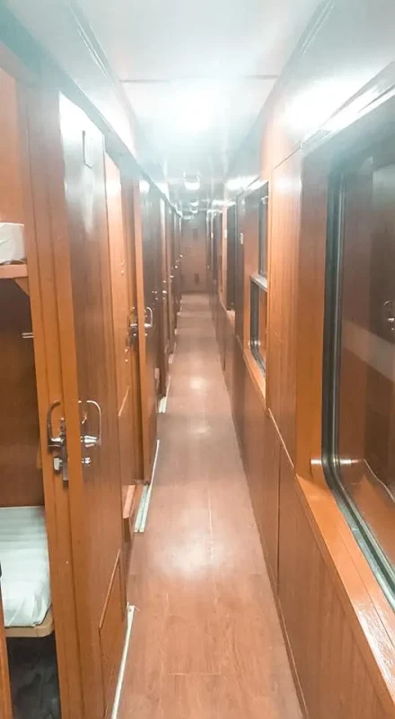 Scams In Vietnam: READ BEFORE YOU VISIT (2025) 16 A corridor inside a Vietnamese sleeper train, with closed cabin doors on one side and windows on the other.