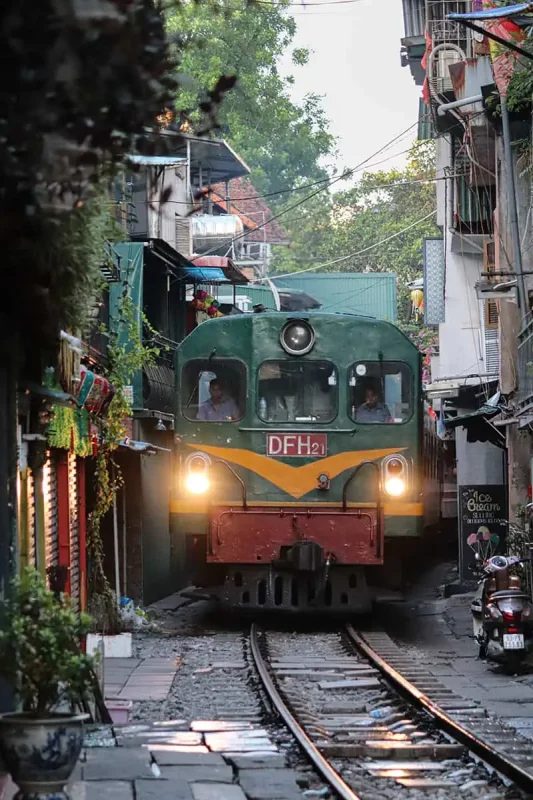 Sleeper train passing through a tight urban alley in Hanoi