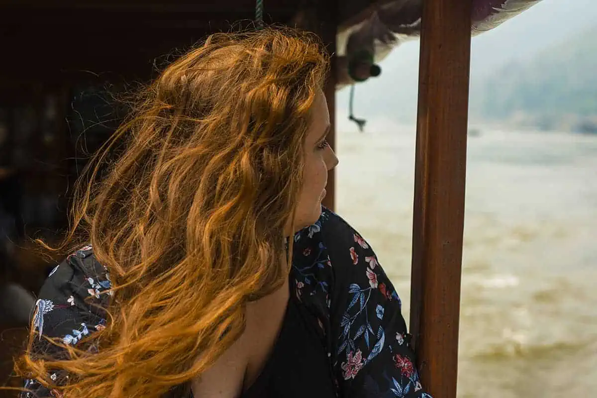 tasha amy with flowing red hair gazes out from the shelter of a slow boat 