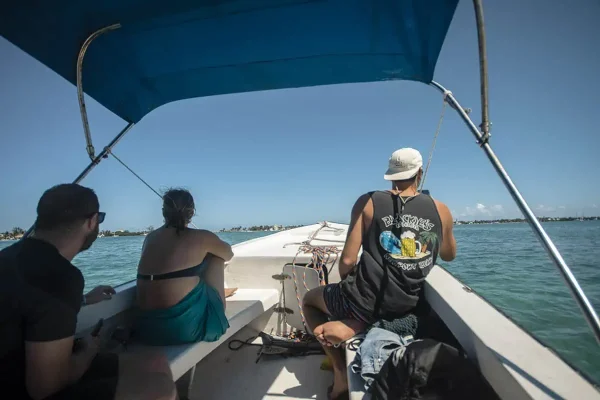 three backpackers sitting on the front of a boat on a caye caulker snorkeling tour