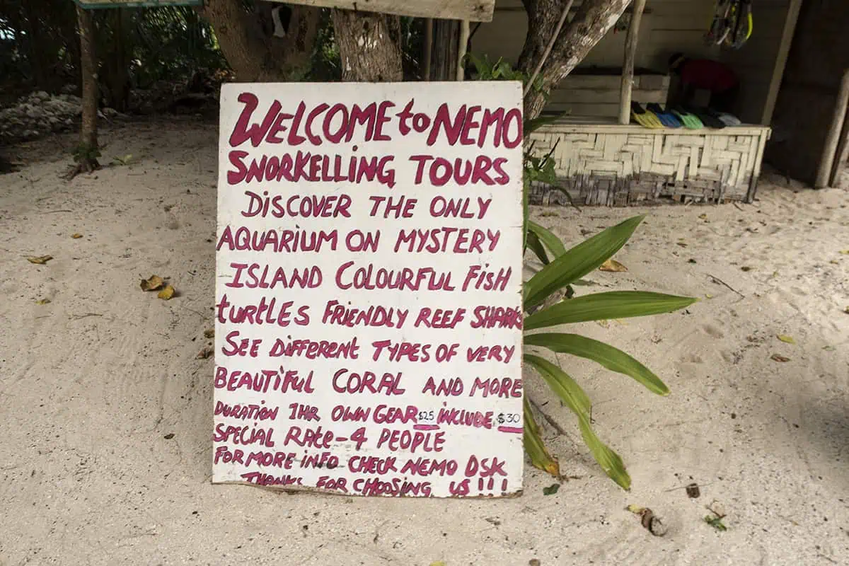A hand-painted sign in the sand advertises Nemo Snorkelling Tours which is one of the best things to do on Mystery Island, inviting visitors to explore coral reefs, colorful fish, and friendly reef sharks.
