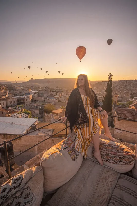tasha amy sits on a bed with pillows and hot air balloons in the sky.