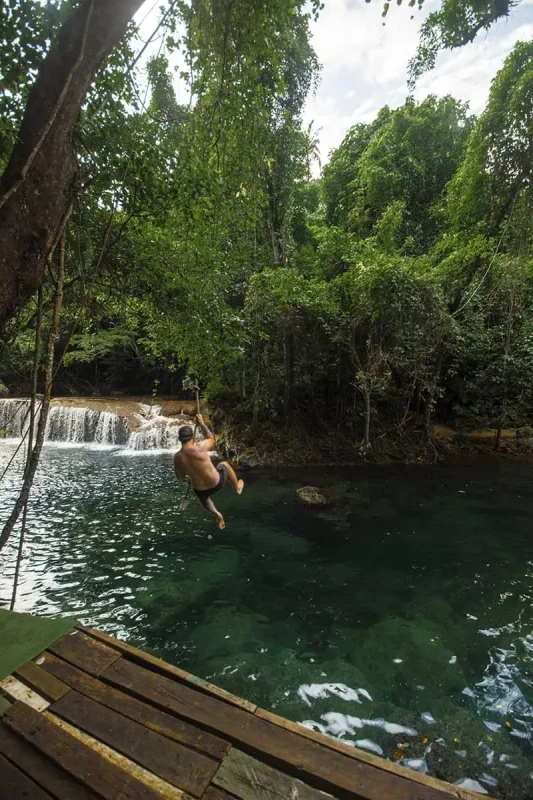a man jumping off a swing rope at rarru cascades in port vila