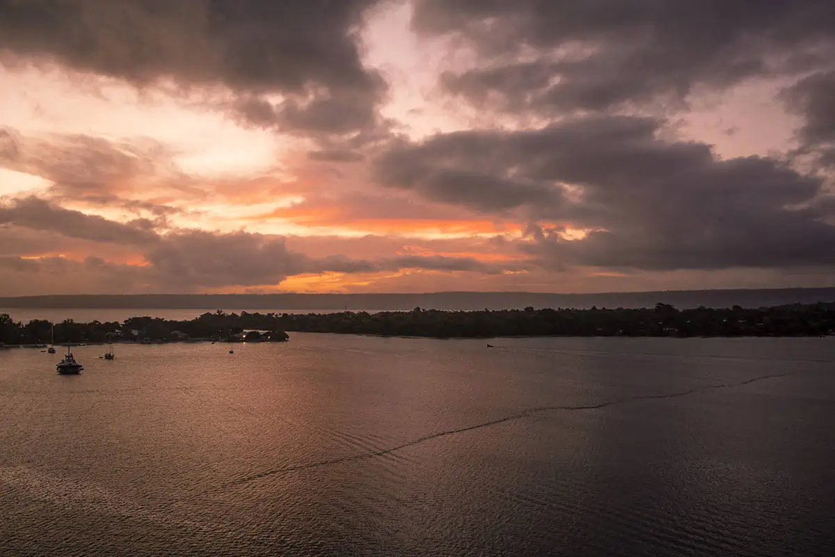 the sunset sky starting to change to pink hues while we cruise past small islands as we leave port vila vanuatu