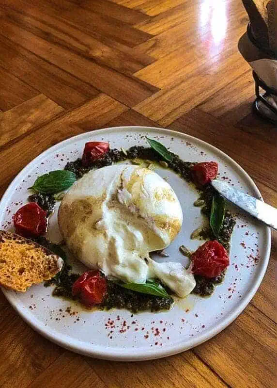 fresh burrata surrounded by pesto and tomato's from popolo luang prabang
