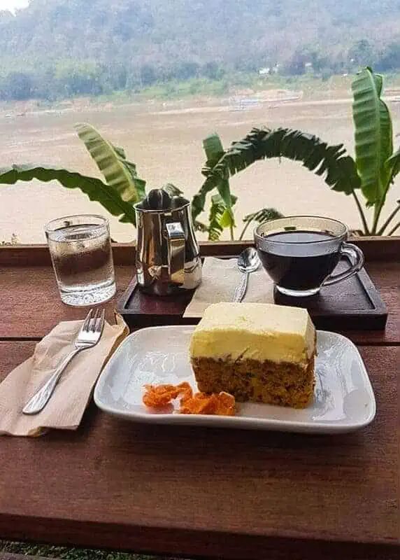 a slice of carrot cake and coffee looking over the river at saffron coffee